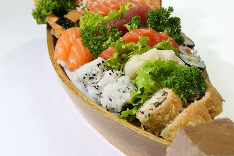 Barca de madeira com sashimis, uramakis e hot rolls
